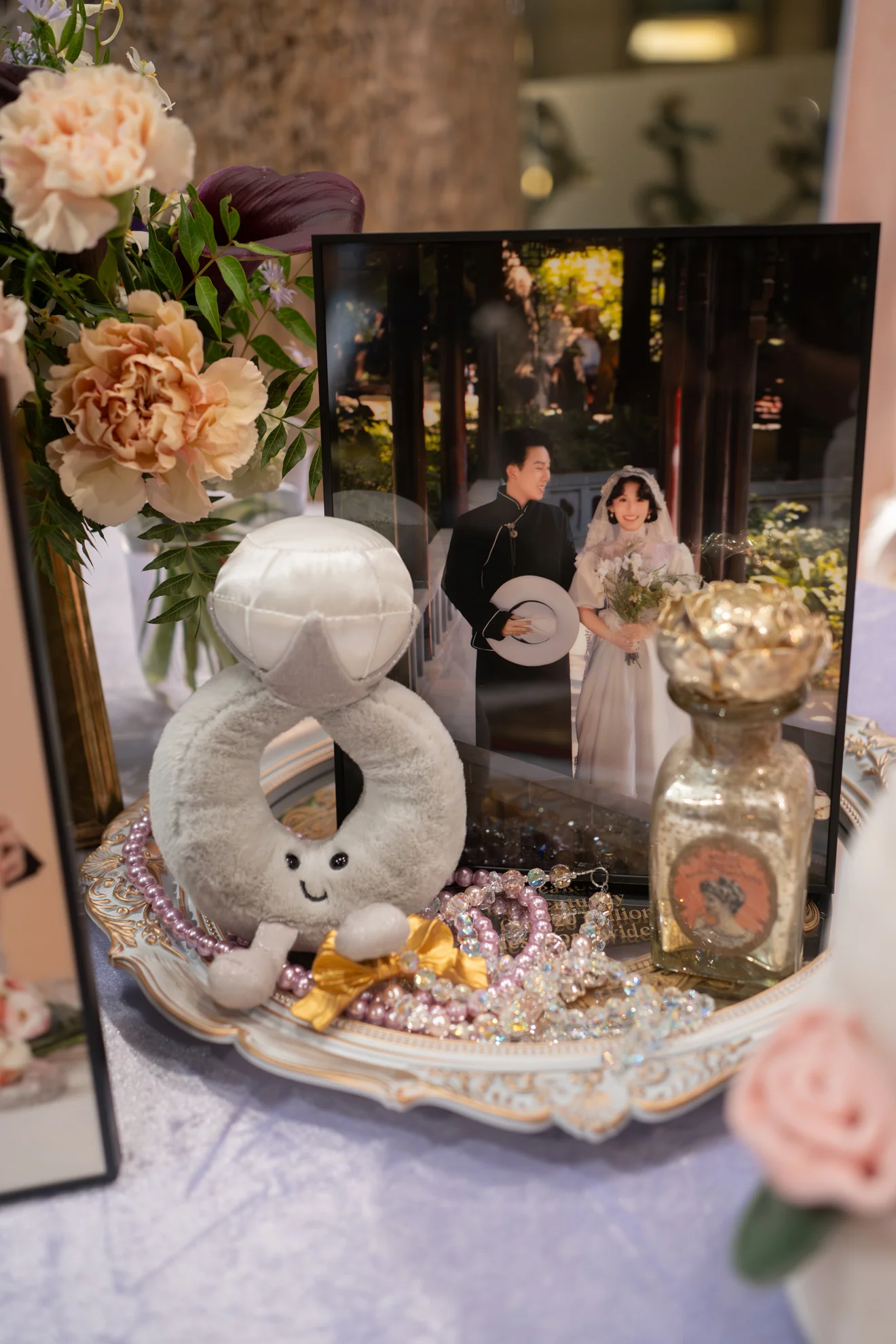 迎賓桌細節:婚紗相框、戒指造型擺件與玫瑰花藝