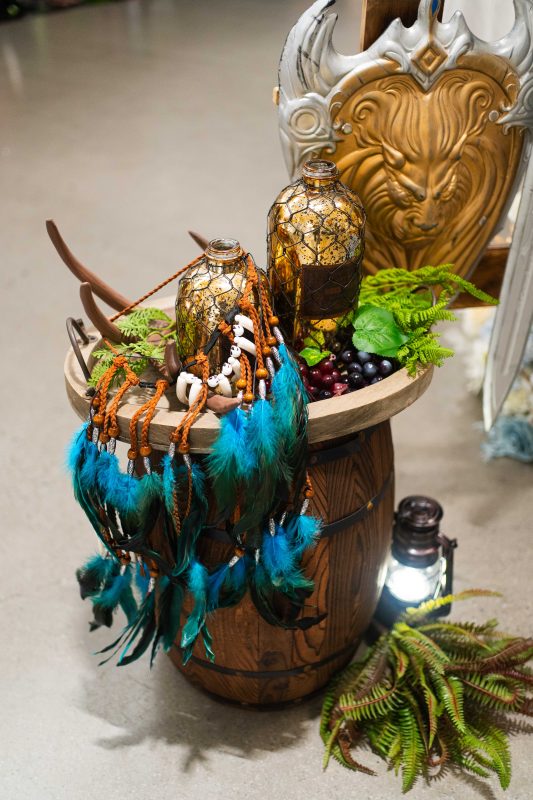 木桶平台上陳列琥珀色瓶、青綠羽飾與燈籠