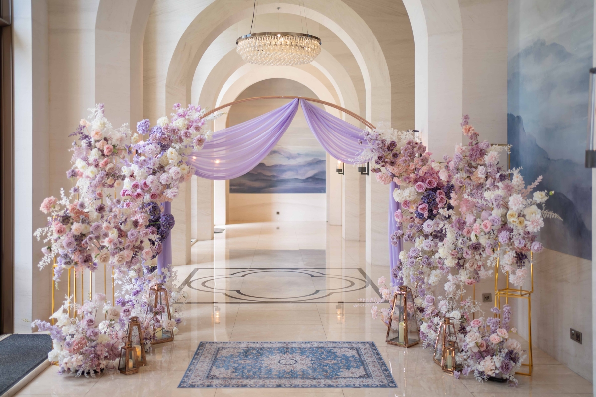 紫色花藝與拱門設計的婚禮迎賓背景，搭配雪紡紗幔打造夢幻場景